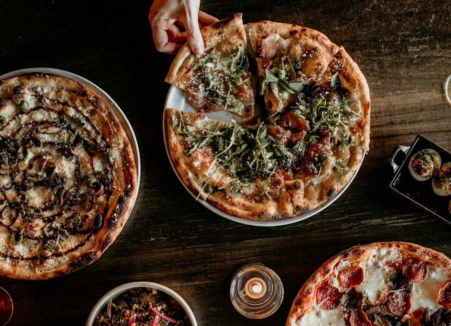 Plusieurs pizzas et assiettes partagées sur une table en bois