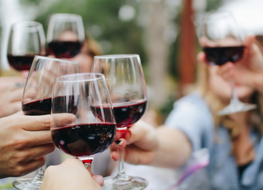 Des amis trinquent avec des verres de vin rouge