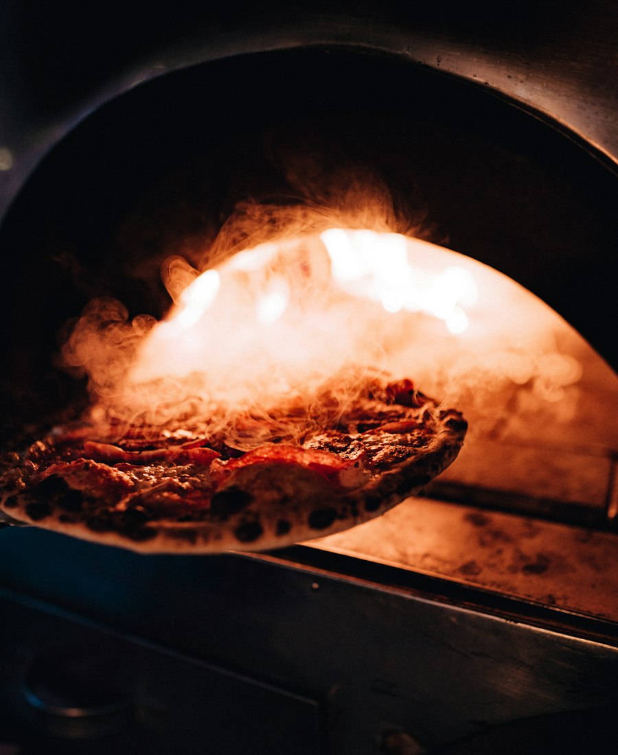 Pizza enfournée dans un four à bois incandescent